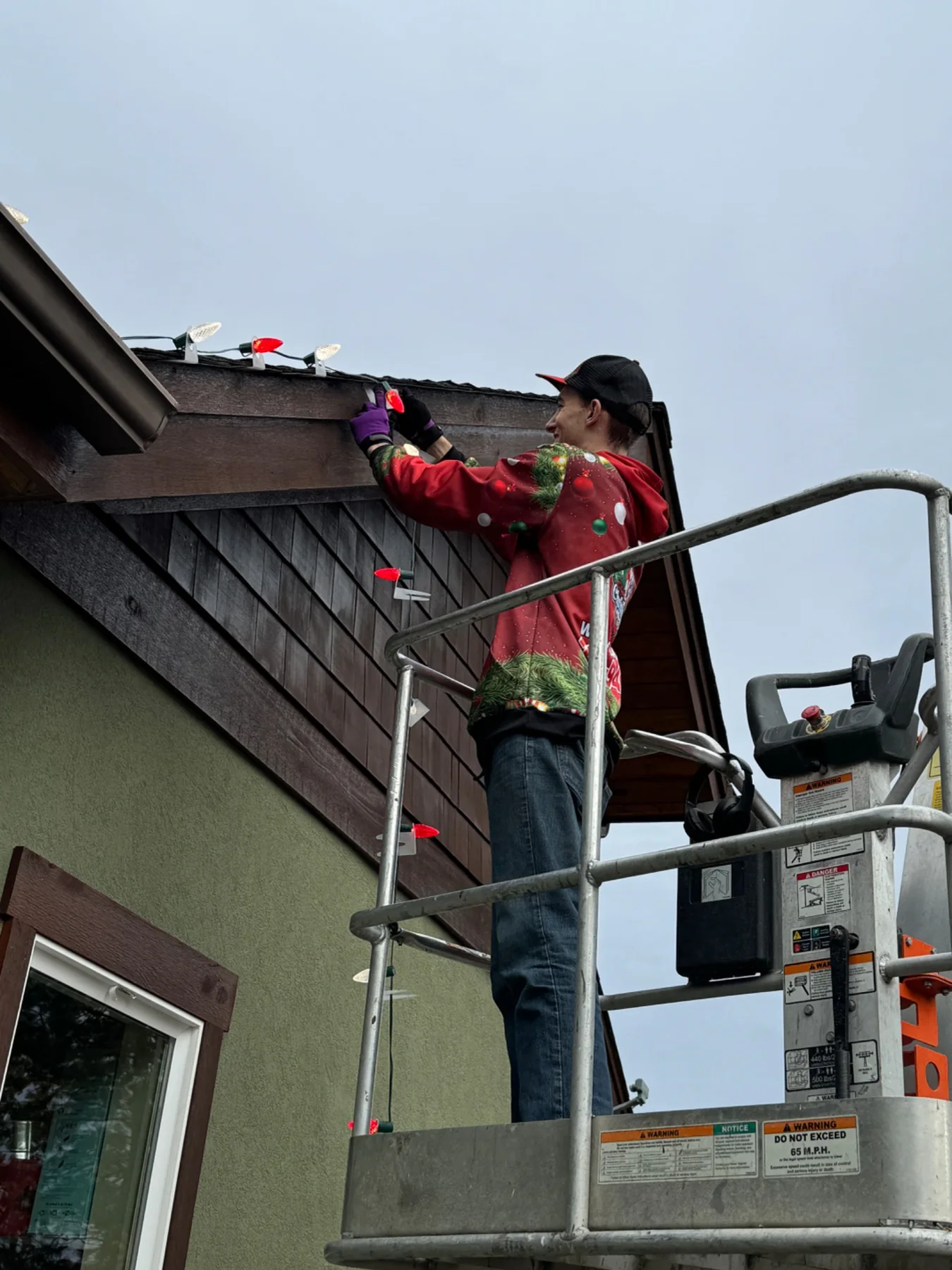 CDA Christmas Lights installing red and white roofline lights from a lift